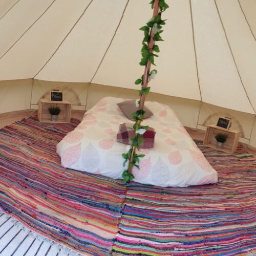 Circular tent with cozy bed and a rug for glamping